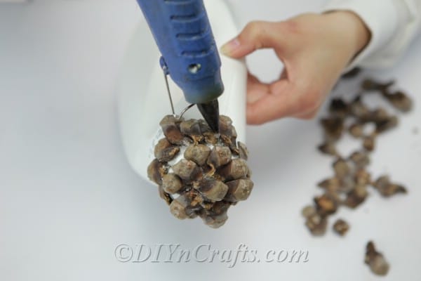 Gluing pinecone pieces to the lid of a detergent bottle