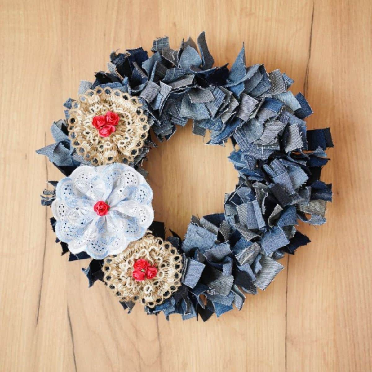 Completed Denim Rag Wreath Project A denim rag wreath embellished with bows, hanging against a rustic wooden wall