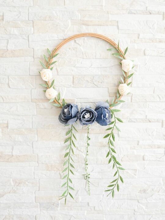 Denim Blooms Door Wreath 4 A collection of crafting supplies for making a denim floral wreath, including old jeans, an embroidery hoop, and fake flowers.