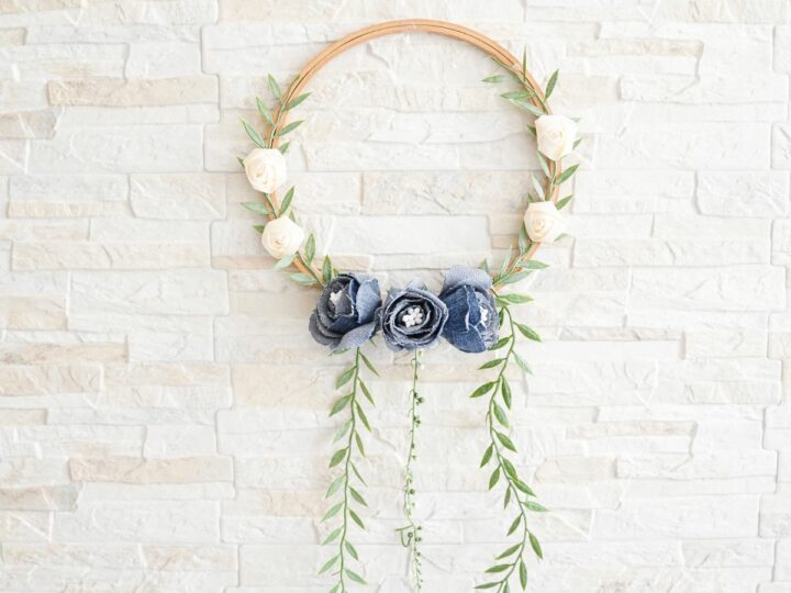 Denim Blooms Door Wreath 3 Close-up of a denim floral door wreath featuring handmade denim roses and delicate artificial greenery on an embroidery hoop.