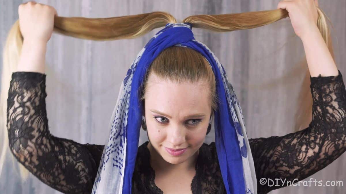 woman tying scarf around high ponytail